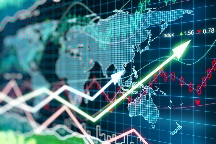 Stock market charts indicating gains and overlapping a digital world map