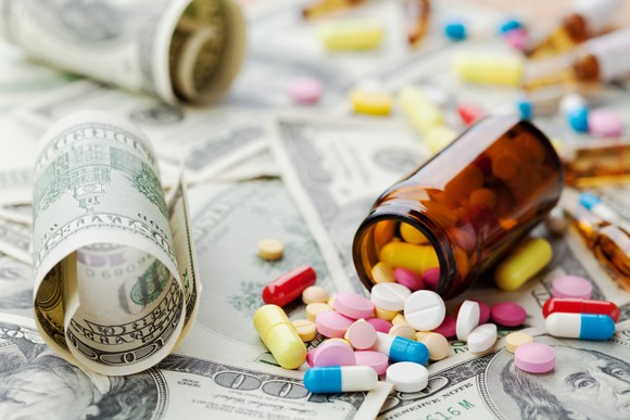 Pills scattered on top of a pile of hundred-dollar bills.