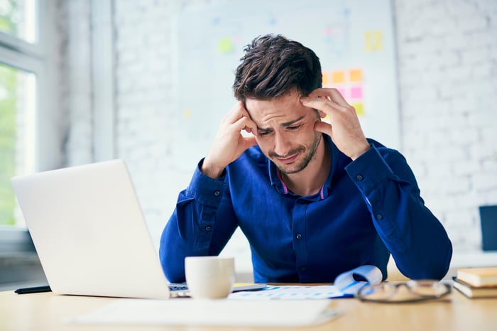 Man at laptop with sorrowful expression.