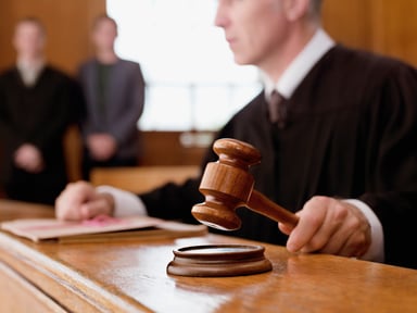 A judge holding gavel in courtroom.