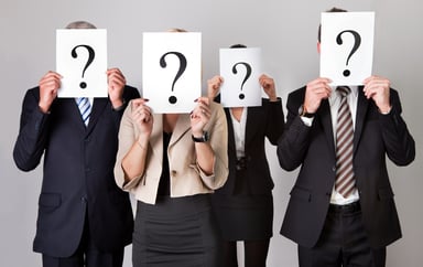 4 business people holding question mark signs