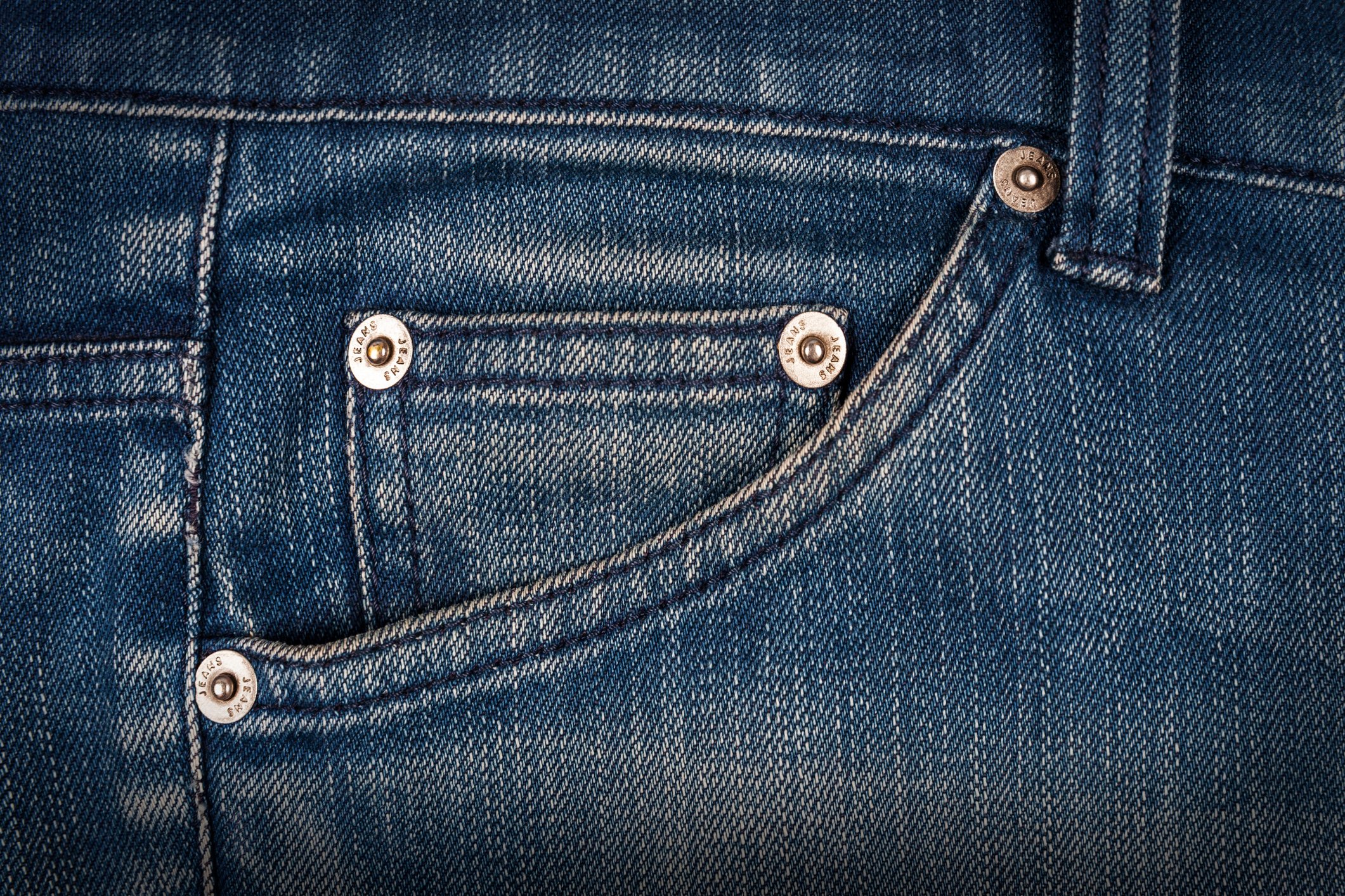 Close up of hip pocket on a pair of weathered blue jeans.