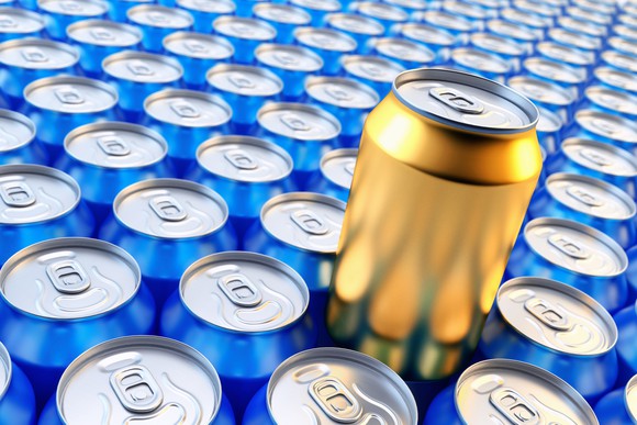 A golden soft drink can standing out among lines of blue cans.