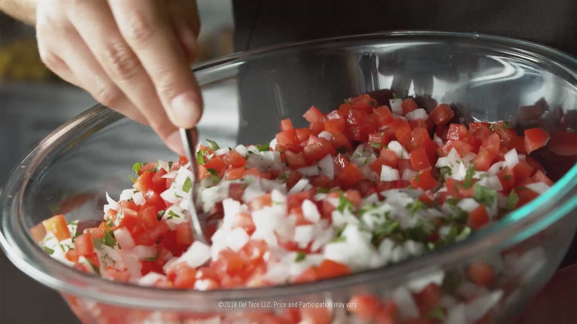 Hand mixing a bowl of salsa.