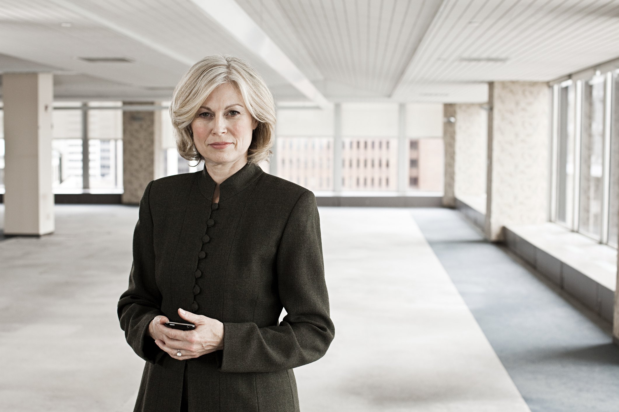 Middle-aged woman with serious expression standing in empty room