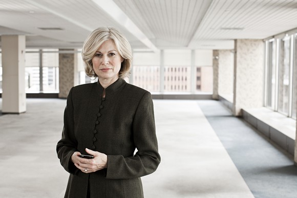 Middle-aged woman with serious expression standing in empty room