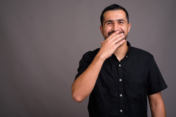 Laughing man with hand over his mouth