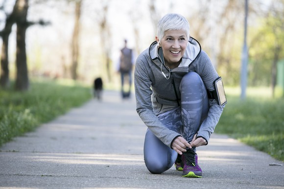 A woman bending down to tie her shoe
