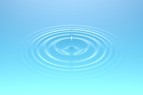 Droplets of water falling into a body of water and creating ripples. Soft light blue-green color.