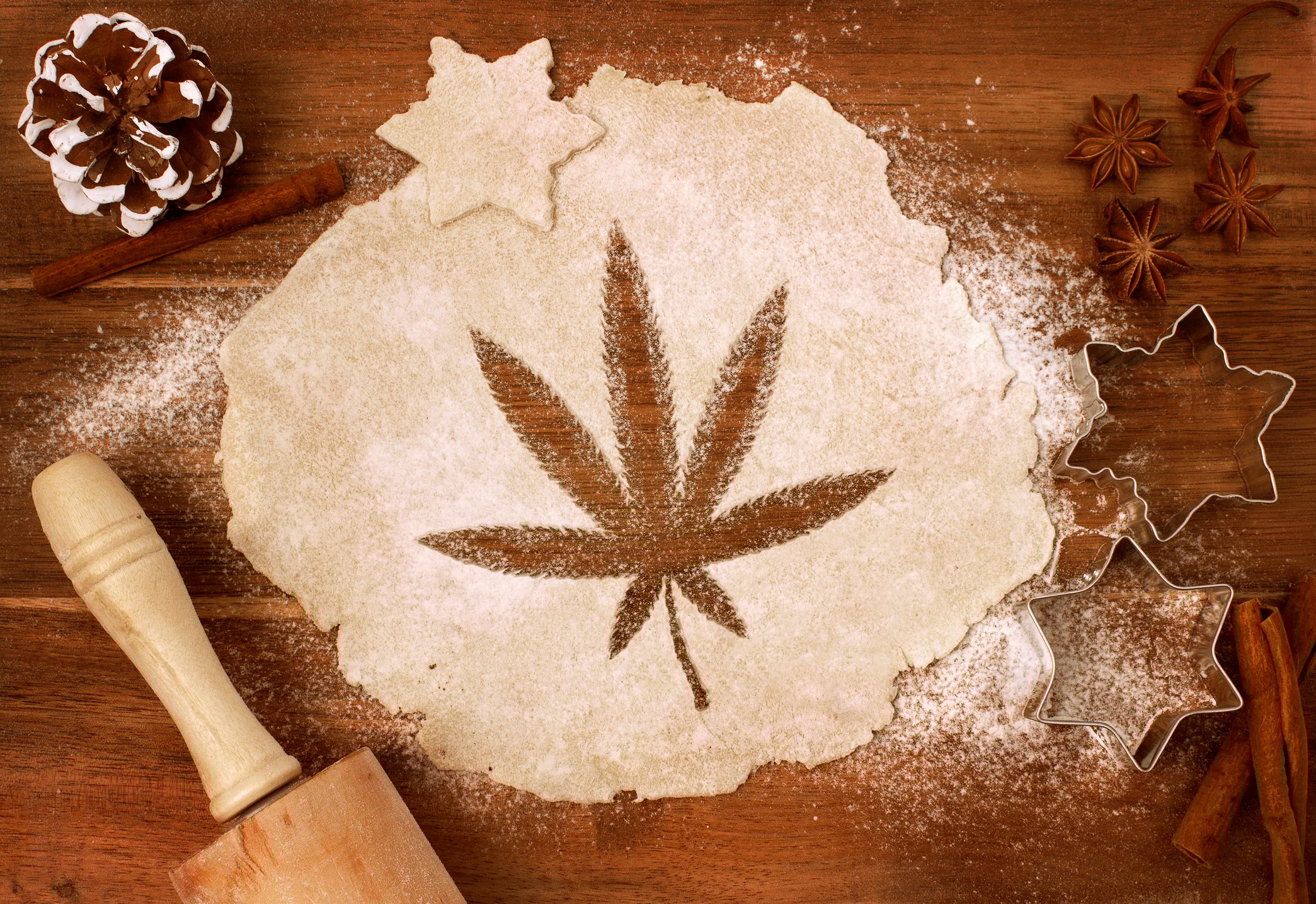 An image of a marijuana leaf cut into rolled-out dough on a baker's table.