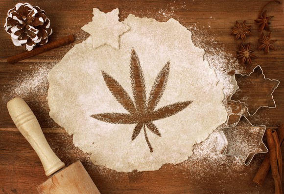 An image of a marijuana leaf cut into rolled-out dough on a baker's table.