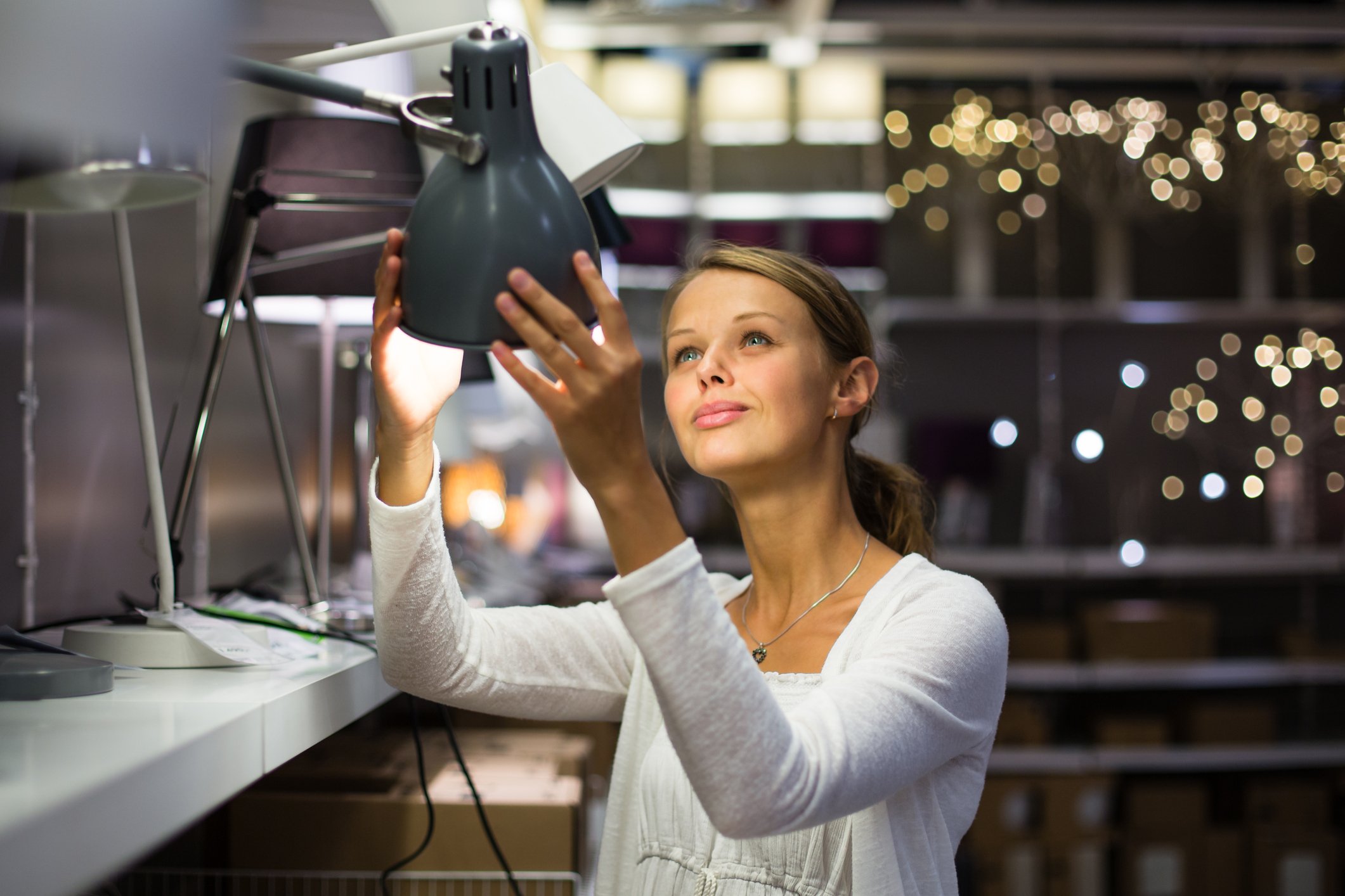 A woman checks a lamp at a home goods store.