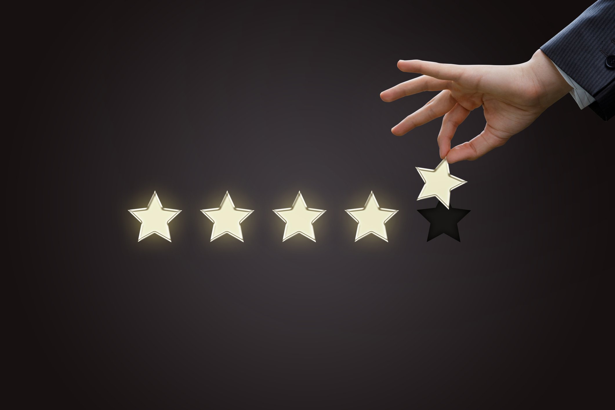 Businessman's hand holding a gold star next to four other stars