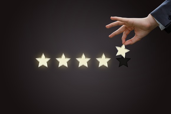 Businessman's hand holding a gold star next to four other stars