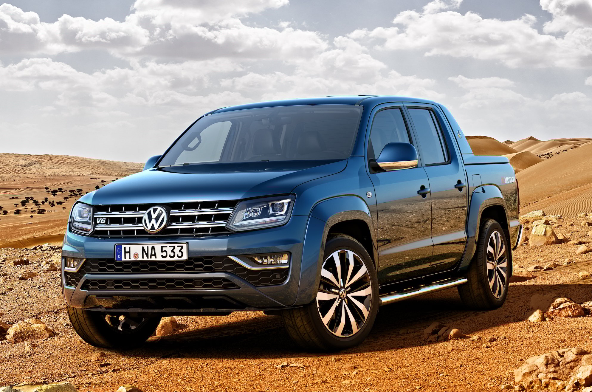 A blue VW Aramok, a midsize pickup, in a desert setting. 