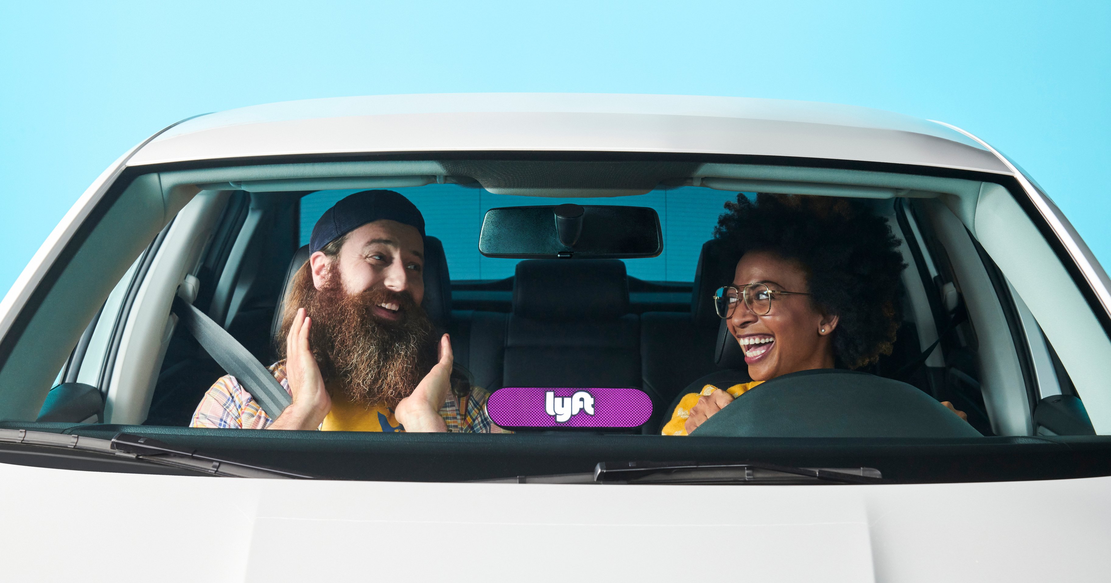 A Lyft driver in a car with a delighted rider.