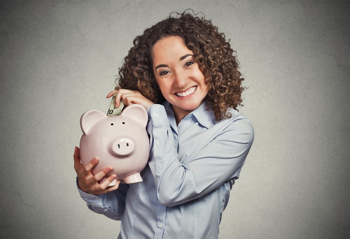 Woman putting money into piggy bank.