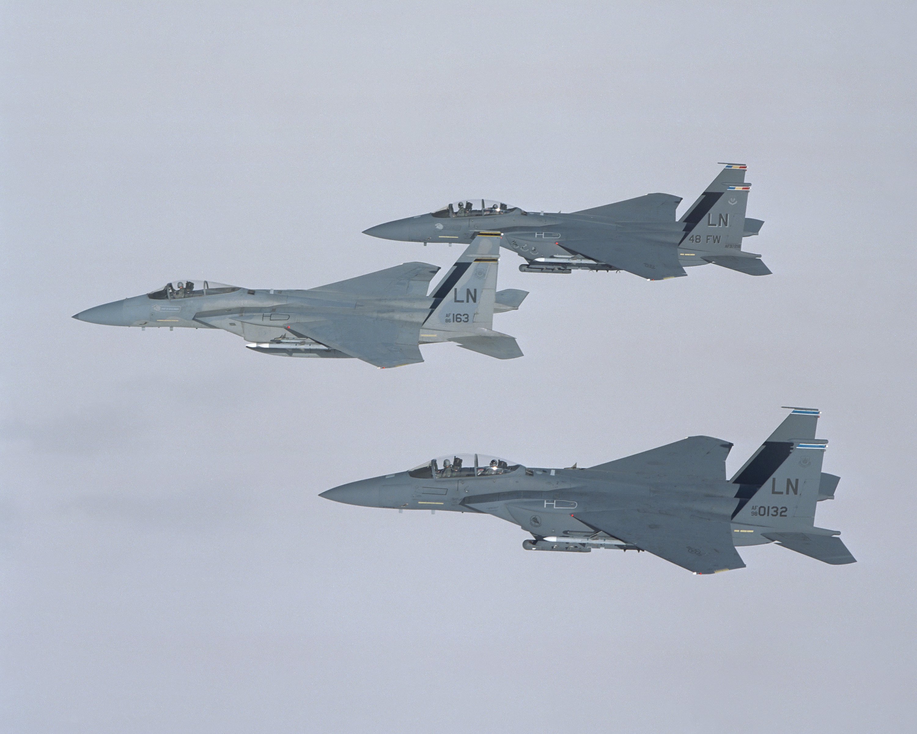 Three Boeing F-15s fly above the clouds.