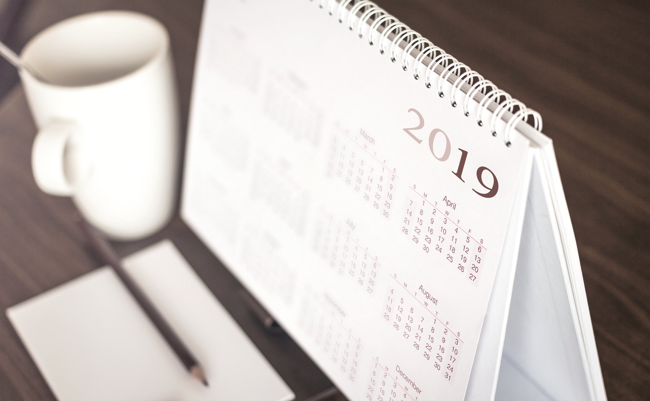 A 2019 calendar beside a mug on a desk.