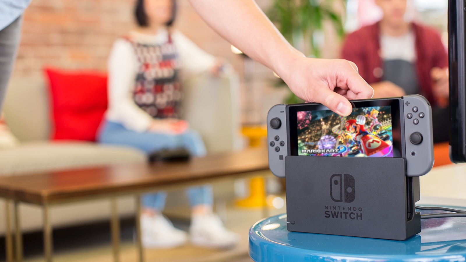 A hand placing a Nintendo Switch into its dock.