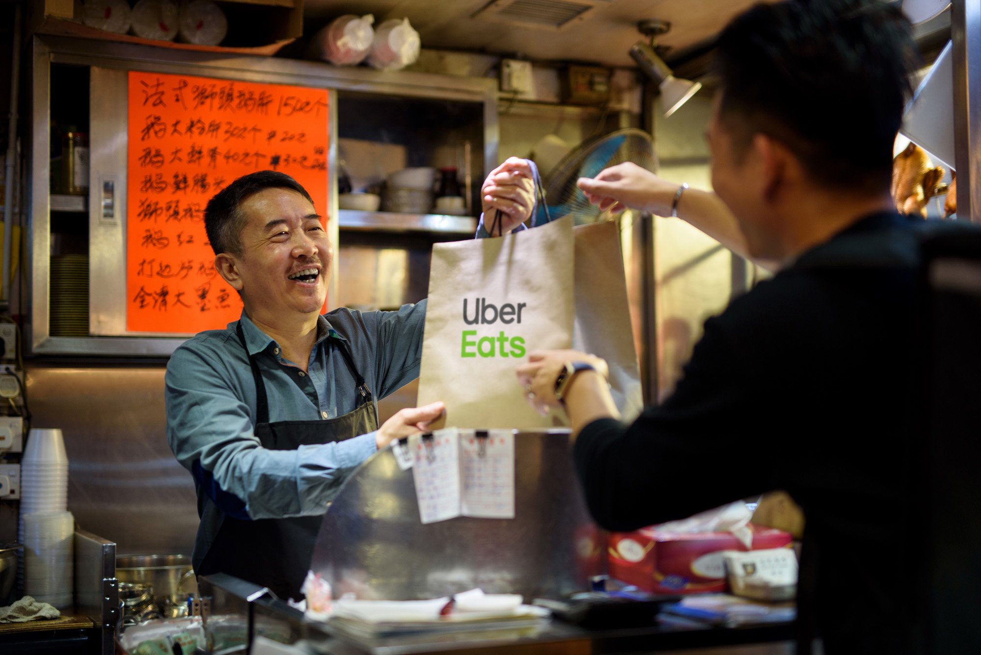 Man handing an "Uber Eats" bag to another man.