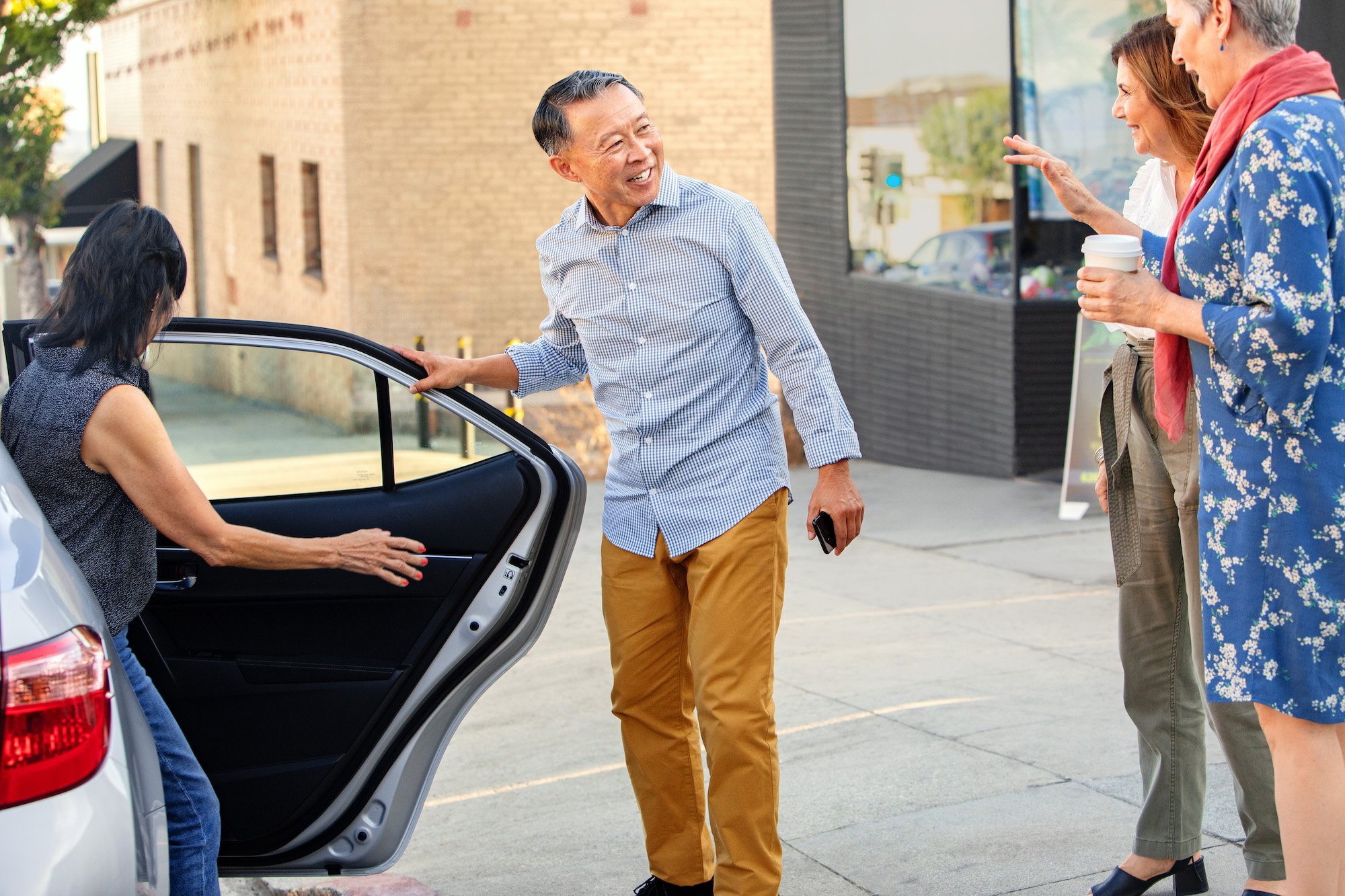 Man opening a car door for people.