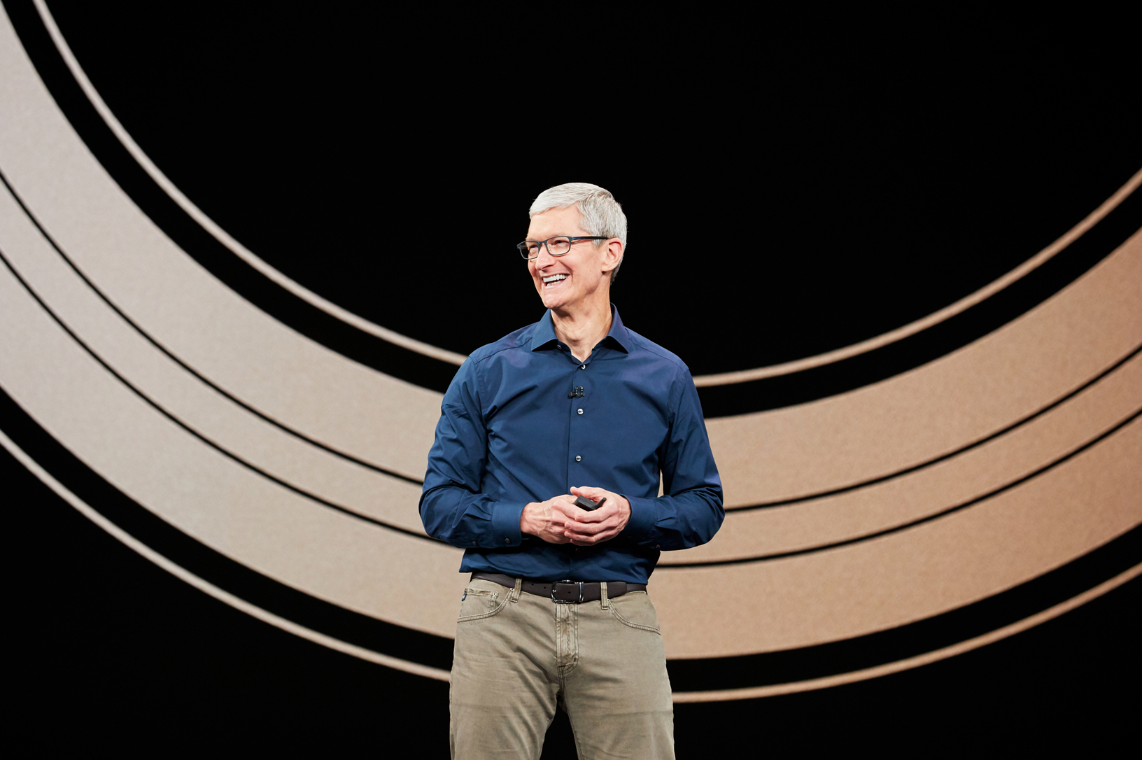 Apple CEO Tim Cook smiling and standing on a stage.