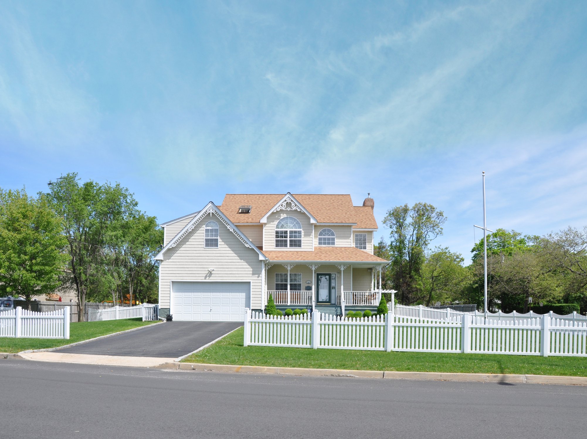 House with white fence around it, with trees in the background
