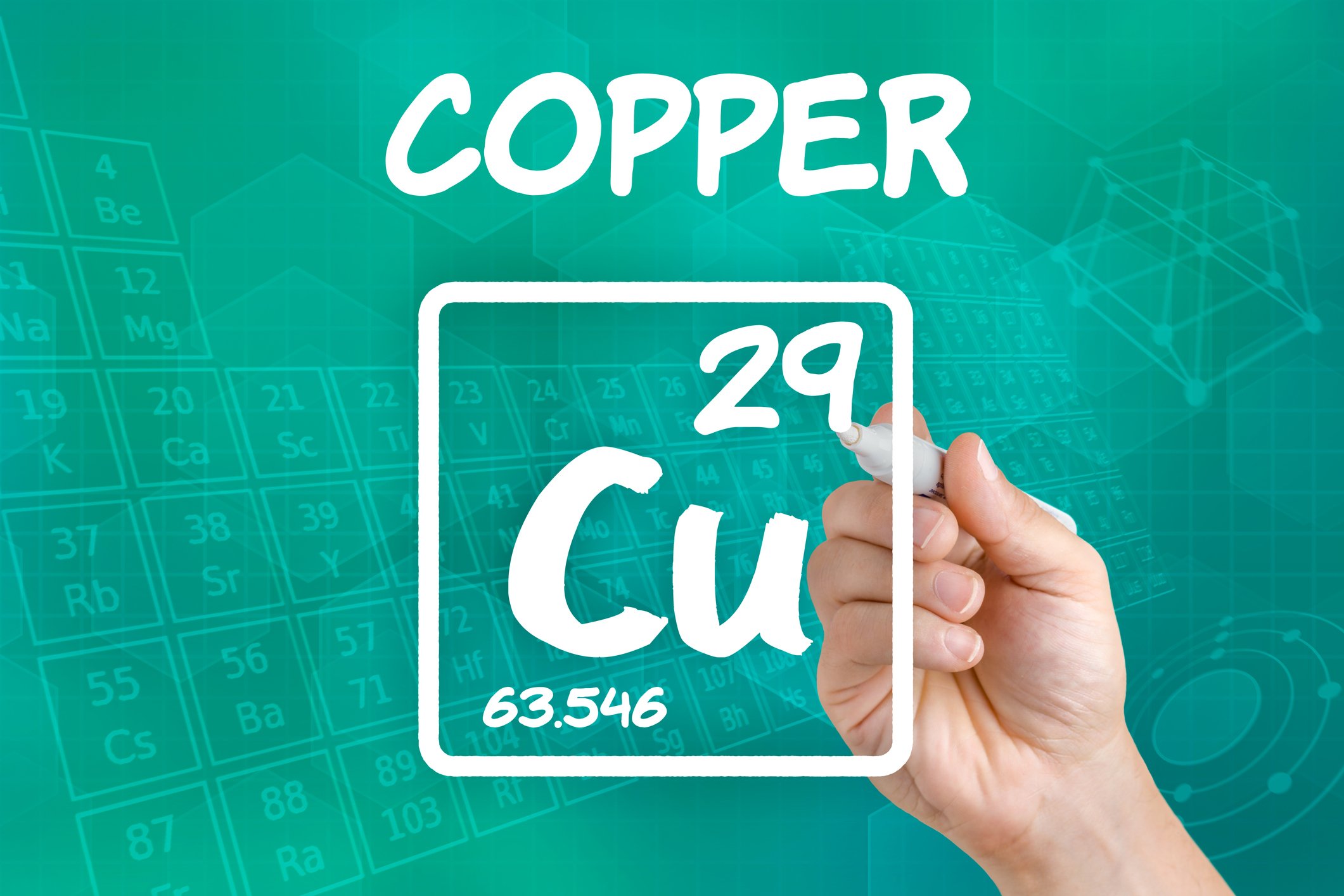 A hand writing the chemical symbol for copper.