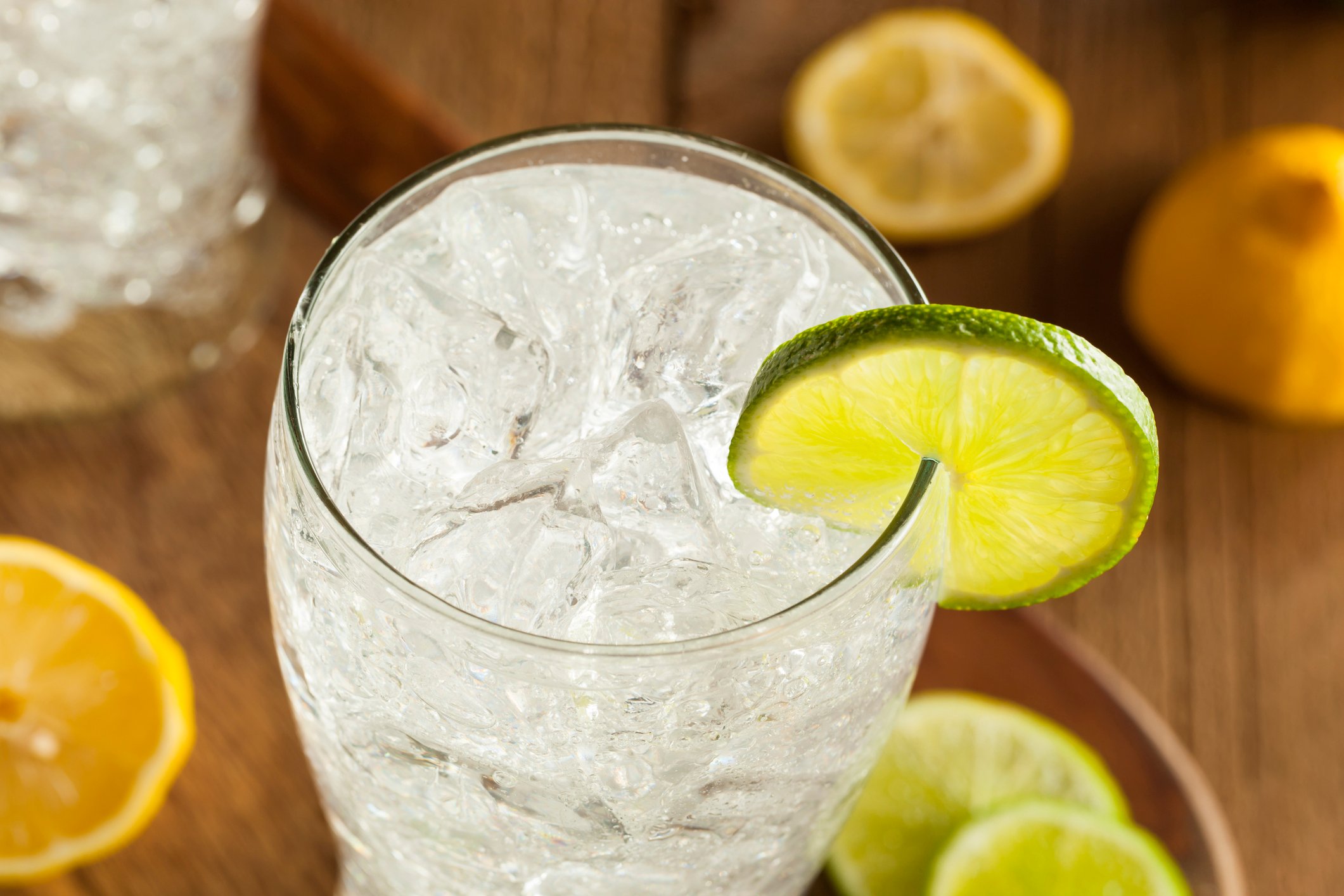 A glass of sparkling water with slices of lemons and limes.