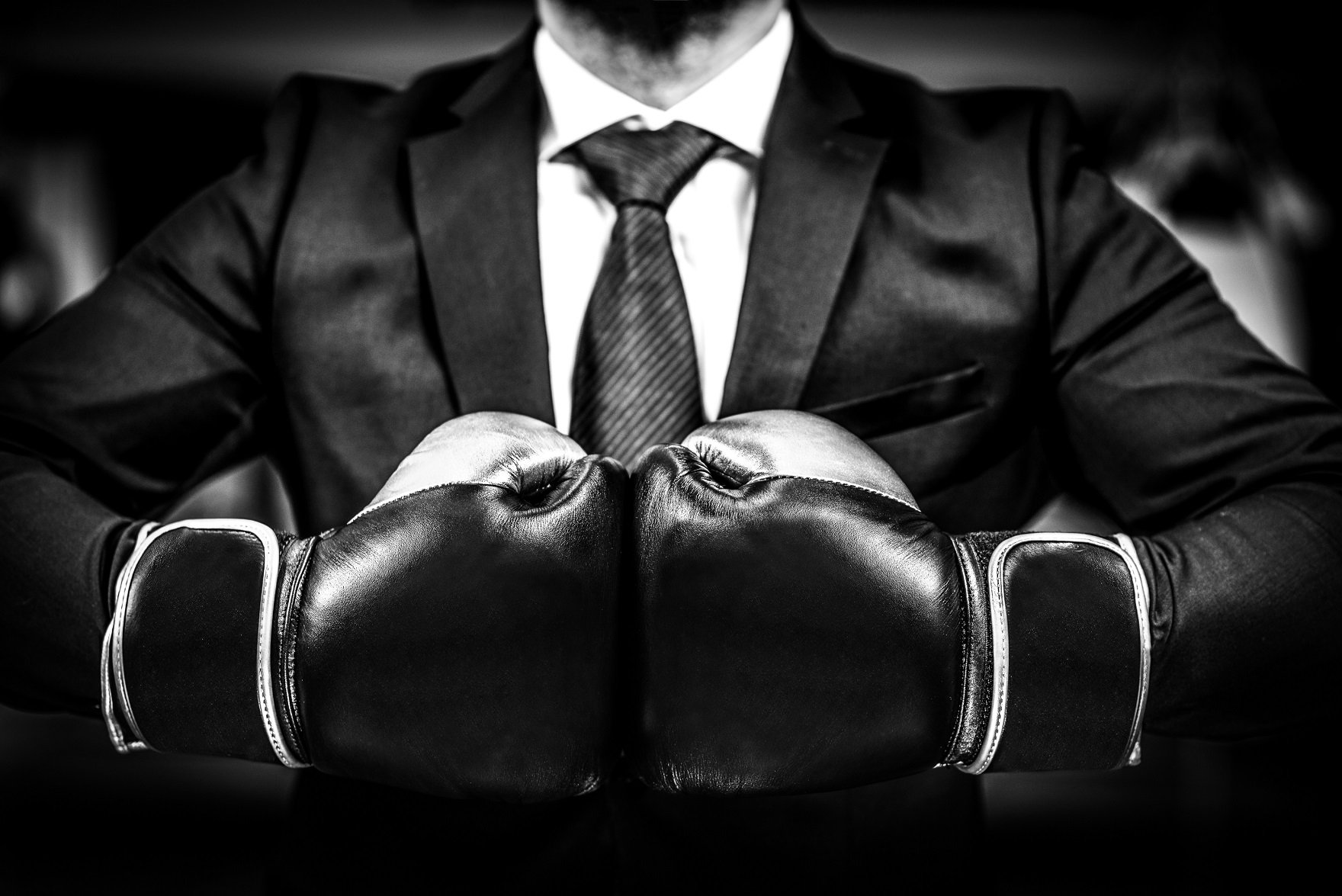 Person in suit wearing boxing gloves held together.