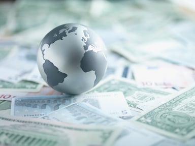 A globe sitting on top several foregin currencies.