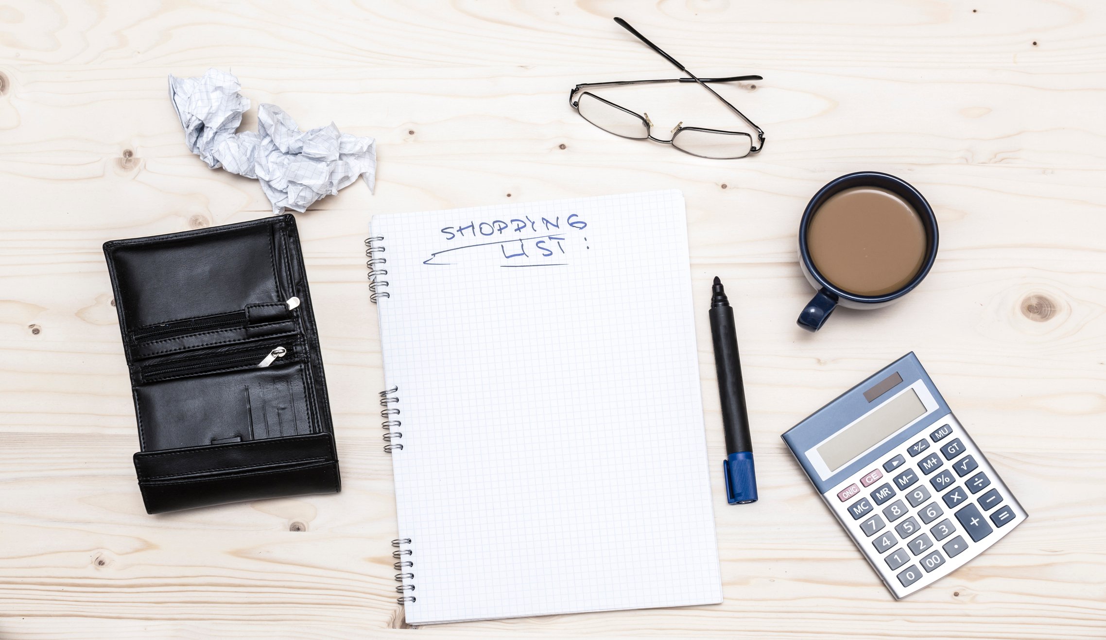 An notebook open to a page titled "shopping list" beside various desk items