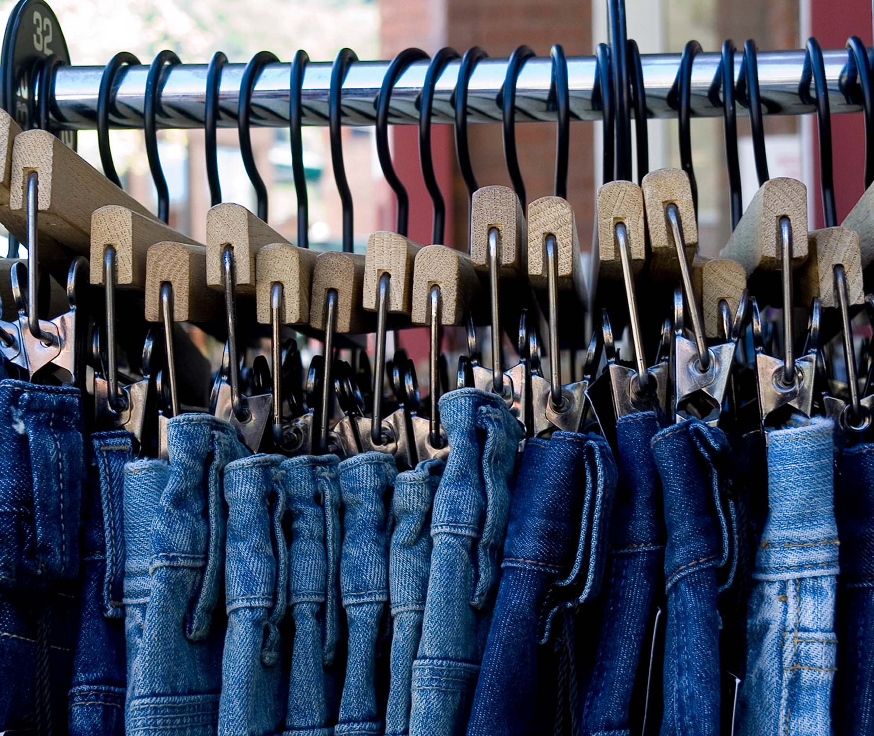 Blue jeans attached to clothes hangers on a store rack