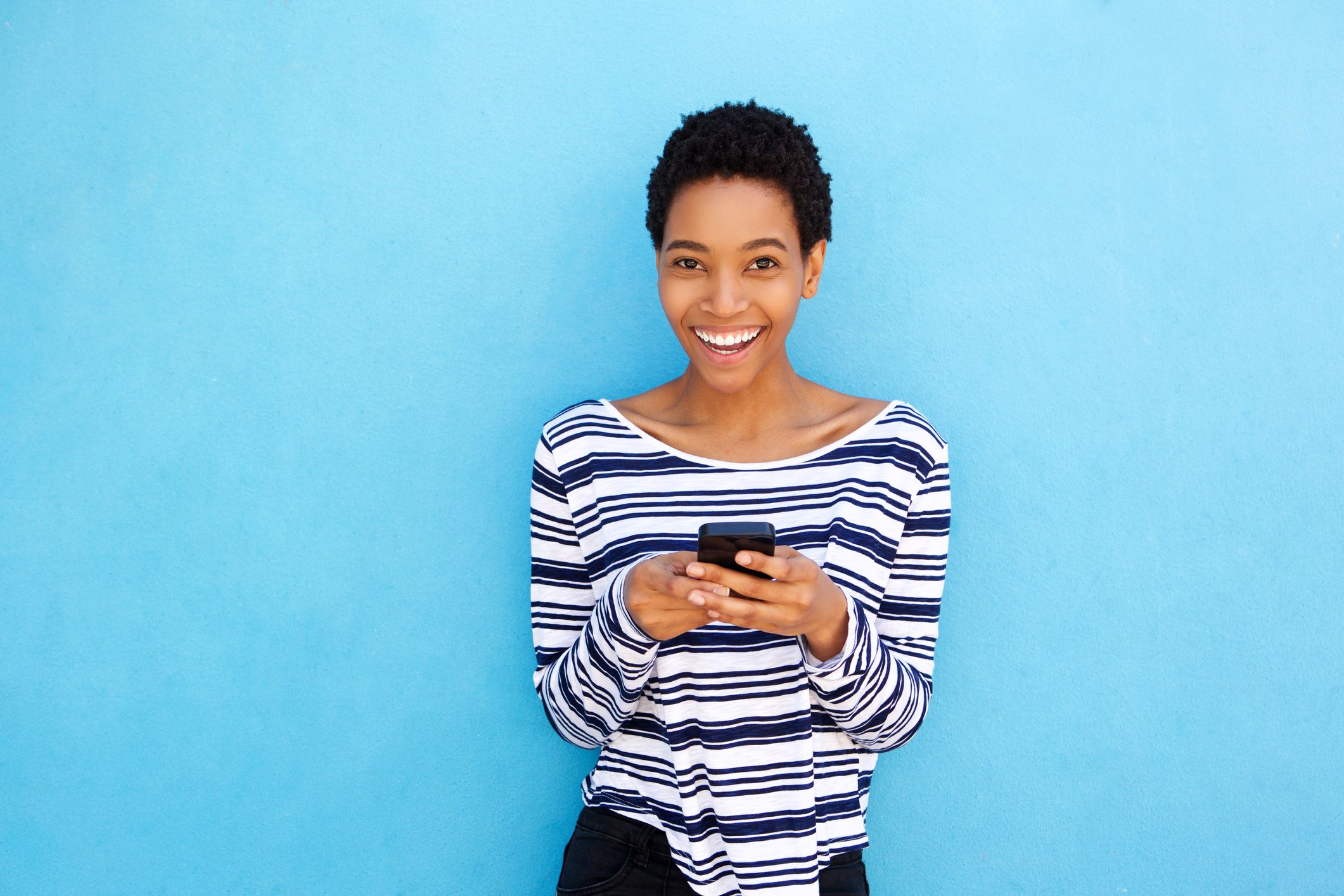 Woman smiling holding a smartphone.