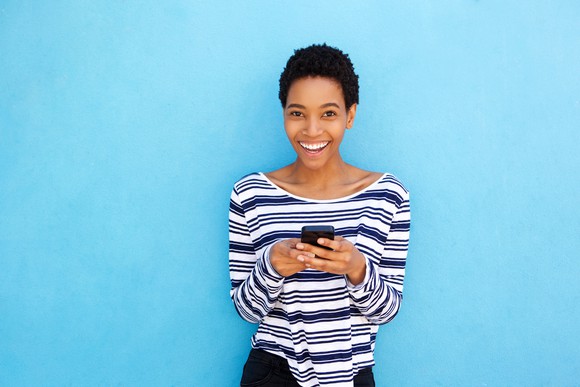 Woman smiling holding a smartphone.