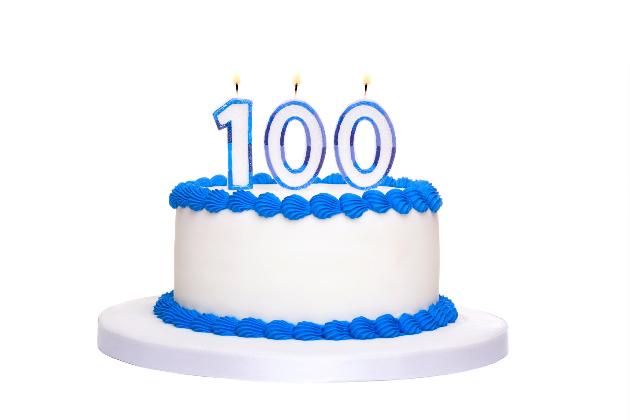 White birthday cake with blue trim and the number 100 in lit candle form on top