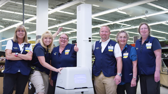 Walmart workers pose with a robot.
