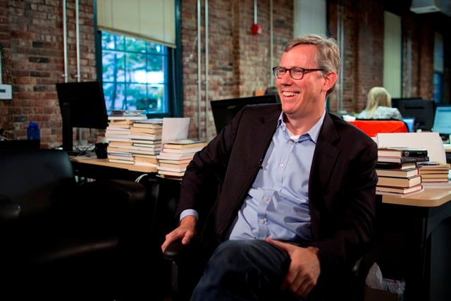 A photo of HubSpot CEO and co-founder Brian Halligan seated at a desk, turned around and facing left.