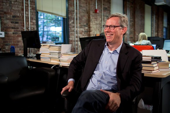 A photo of HubSpot CEO and co-founder Brian Halligan seated at a desk, turned around and facing left.