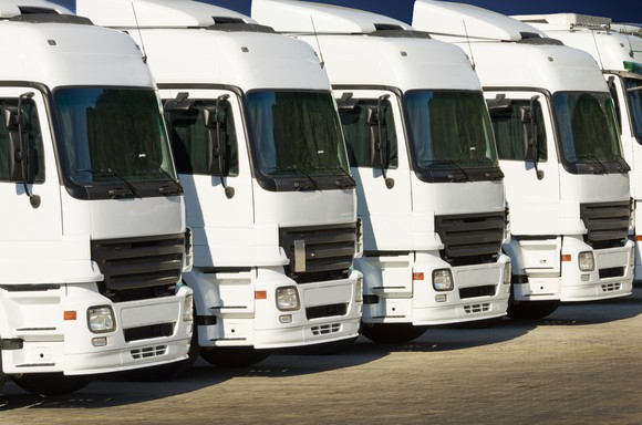 A row of white commercial heavy trucks parked side by side.