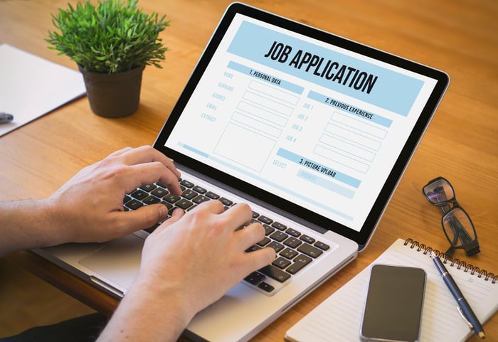 Man typing on laptop with job application up on screen