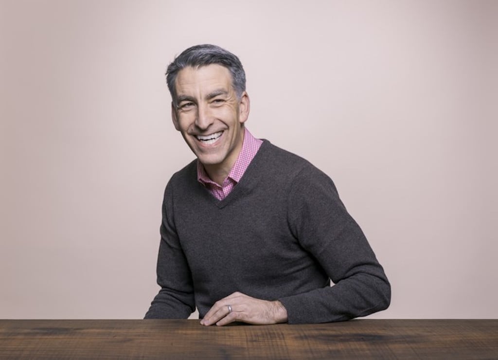 Profile photo of Redfin CEO Glenn Kelman sitting, left hand on a table.