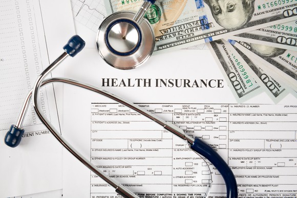 Cash, a stethoscope, and health insurance forms.