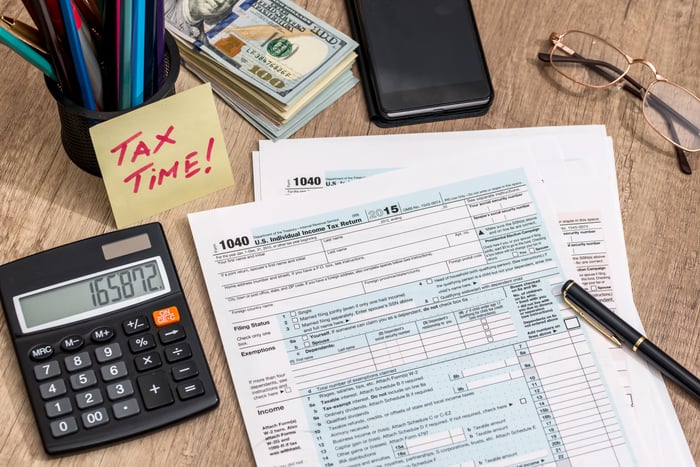 A calculator sits next to tax forms.
