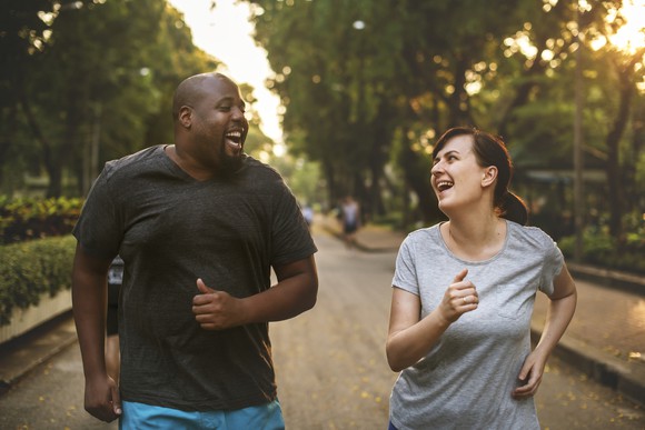 Two people out for a run smiling at each other.