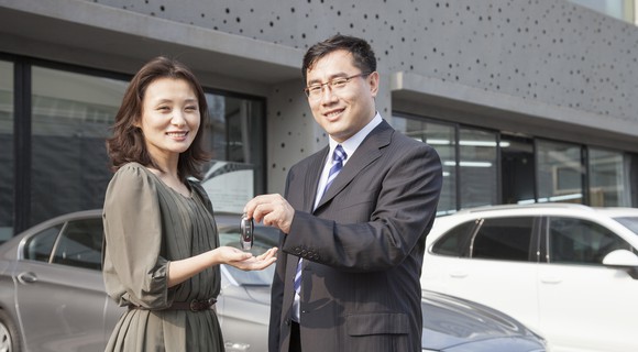 A salesman hands the keys of a car to a customer.