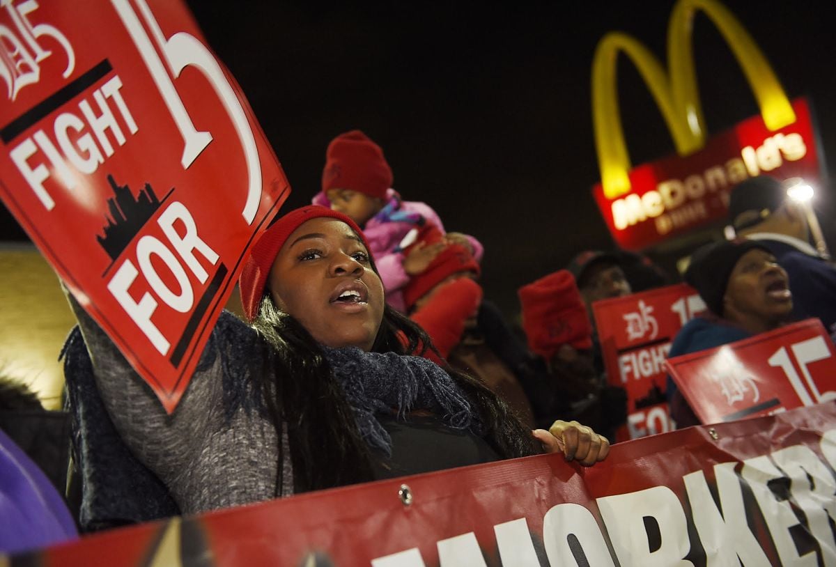 People protest to raise the minimum wage in front of a McDonald's.
