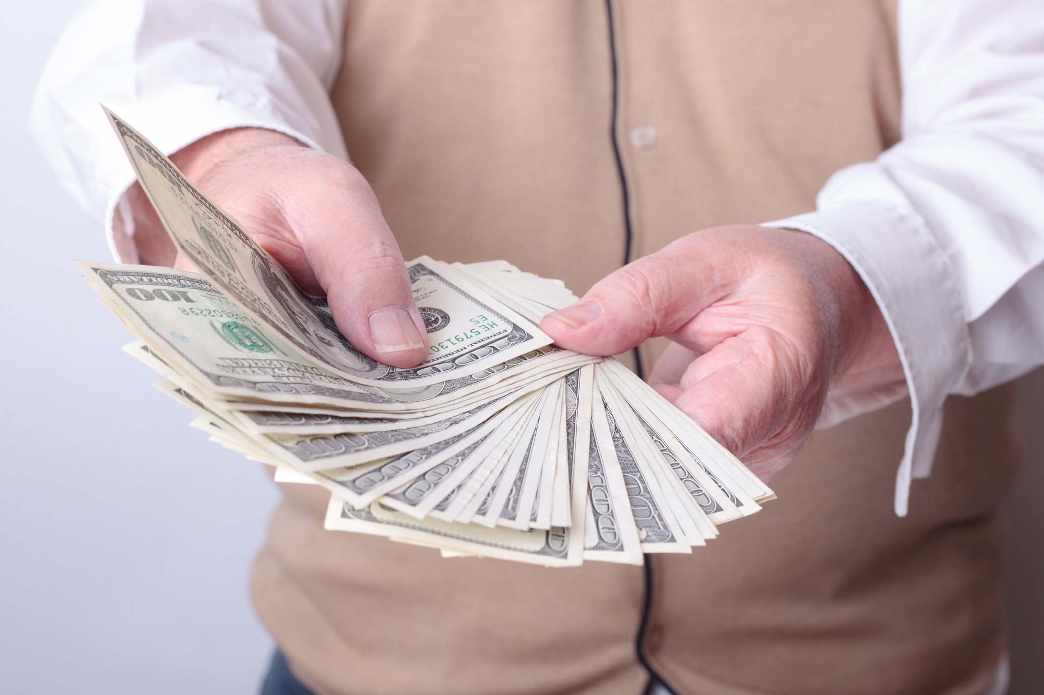 Older man fanning out a bunch of $100 bills