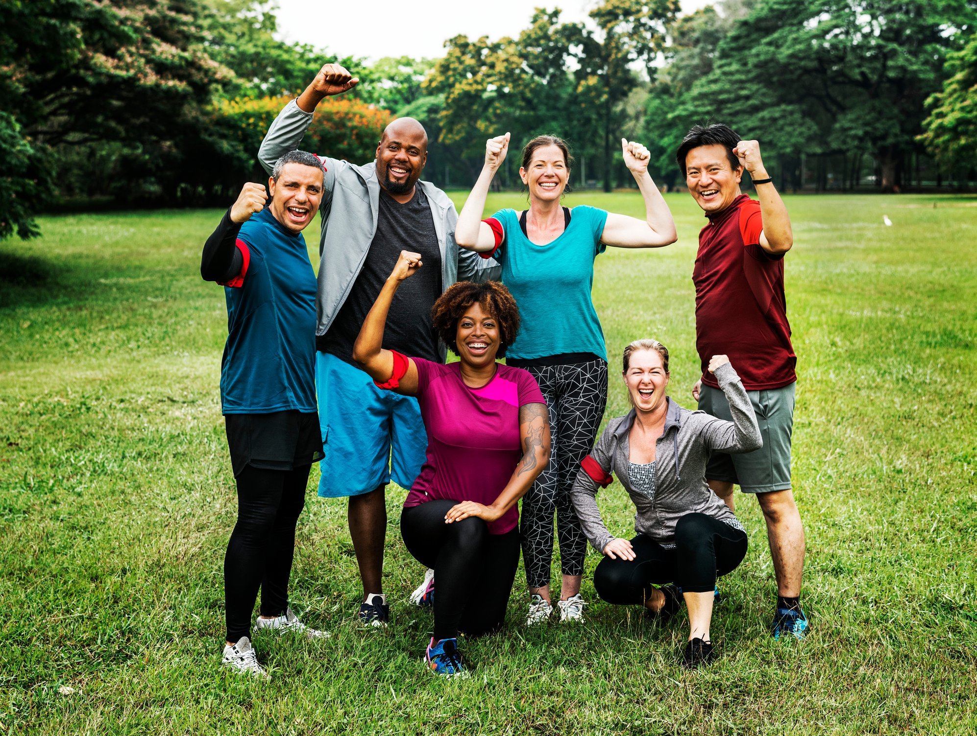Group of people in workout clothes posing with muscles flexing.